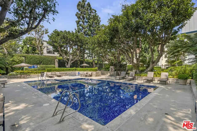 a view of swimming pool with outdoor seating and trees in the background