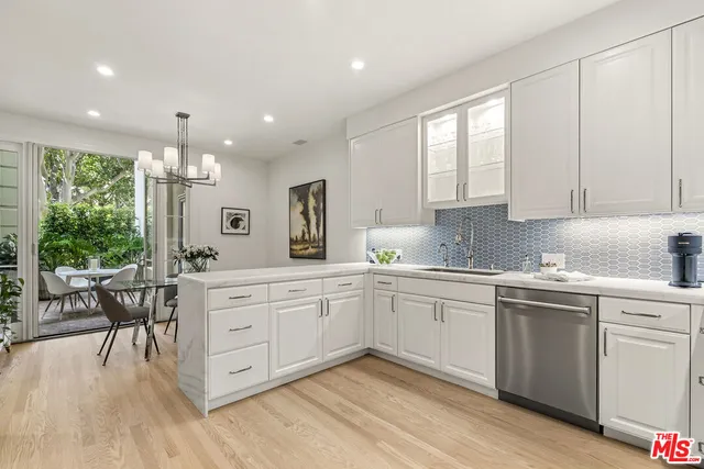a kitchen with white cabinets stainless steel appliances dining table and chairs