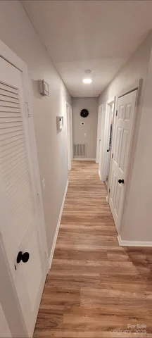 a view of a hallway with wooden floor and staircase