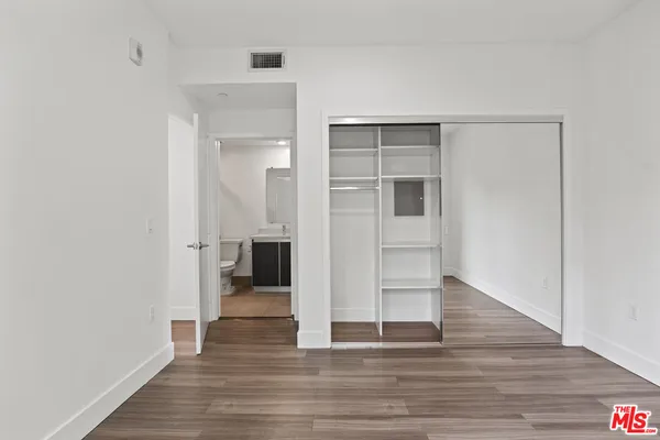 a view of a hallway with wooden floor and closet