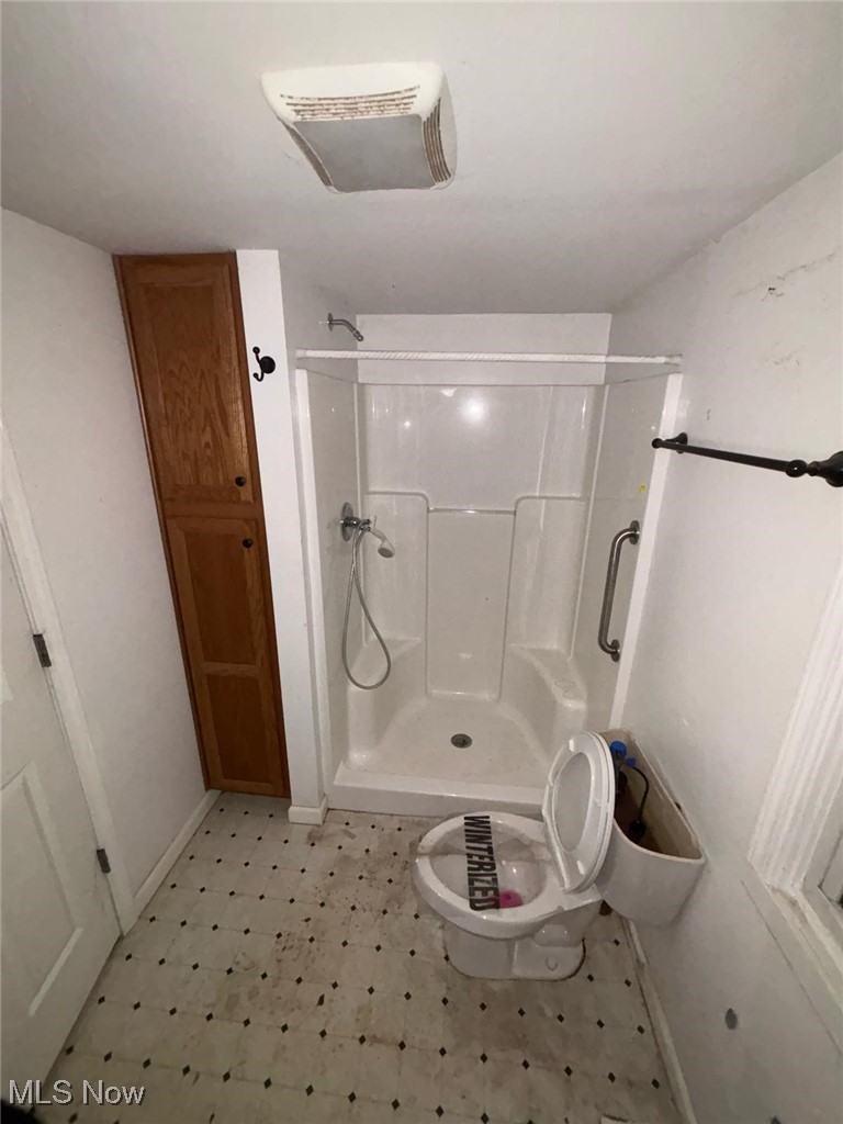 Full bathroom with a shower stall, toilet, and tile patterned floors
