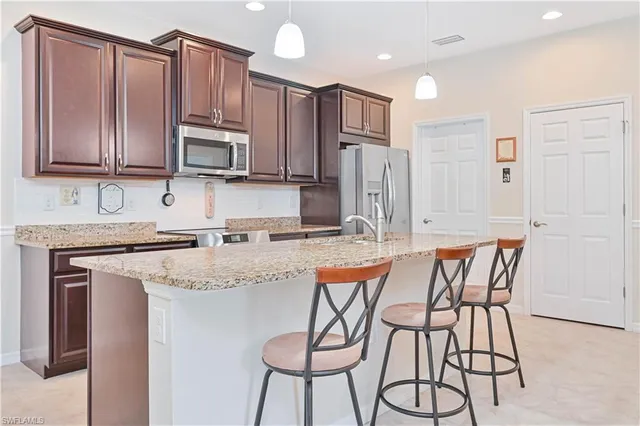 a kitchen with stainless steel appliances granite countertop a stove top oven a refrigerator a sink and dishwasher with wooden cabinets