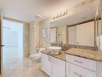a spacious bathroom with a granite countertop sink a toilet a mirror and shower