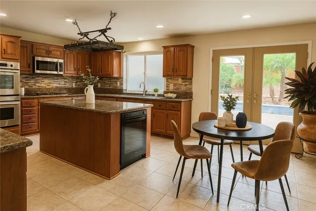 a kitchen with stainless steel appliances granite countertop a stove a sink a microwave a dining table and chairs