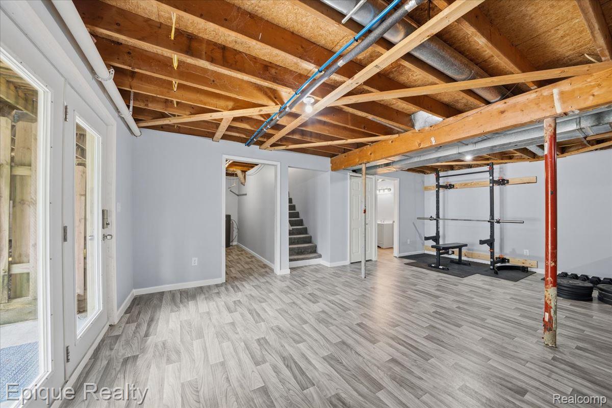 12272 East Mt Morris Road Davison, MI 48423 - Photo 25 of 39 Finished basement space featuring light wood-finish flooring, light gray walls, an exposed beam ceiling, and a French door entrance