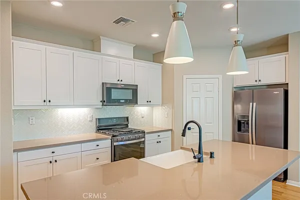 a kitchen with stainless steel appliances a refrigerator a sink a stove a microwave and cabinets