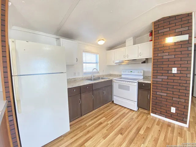 a kitchen with a sink a refrigerator a window and cabinets
