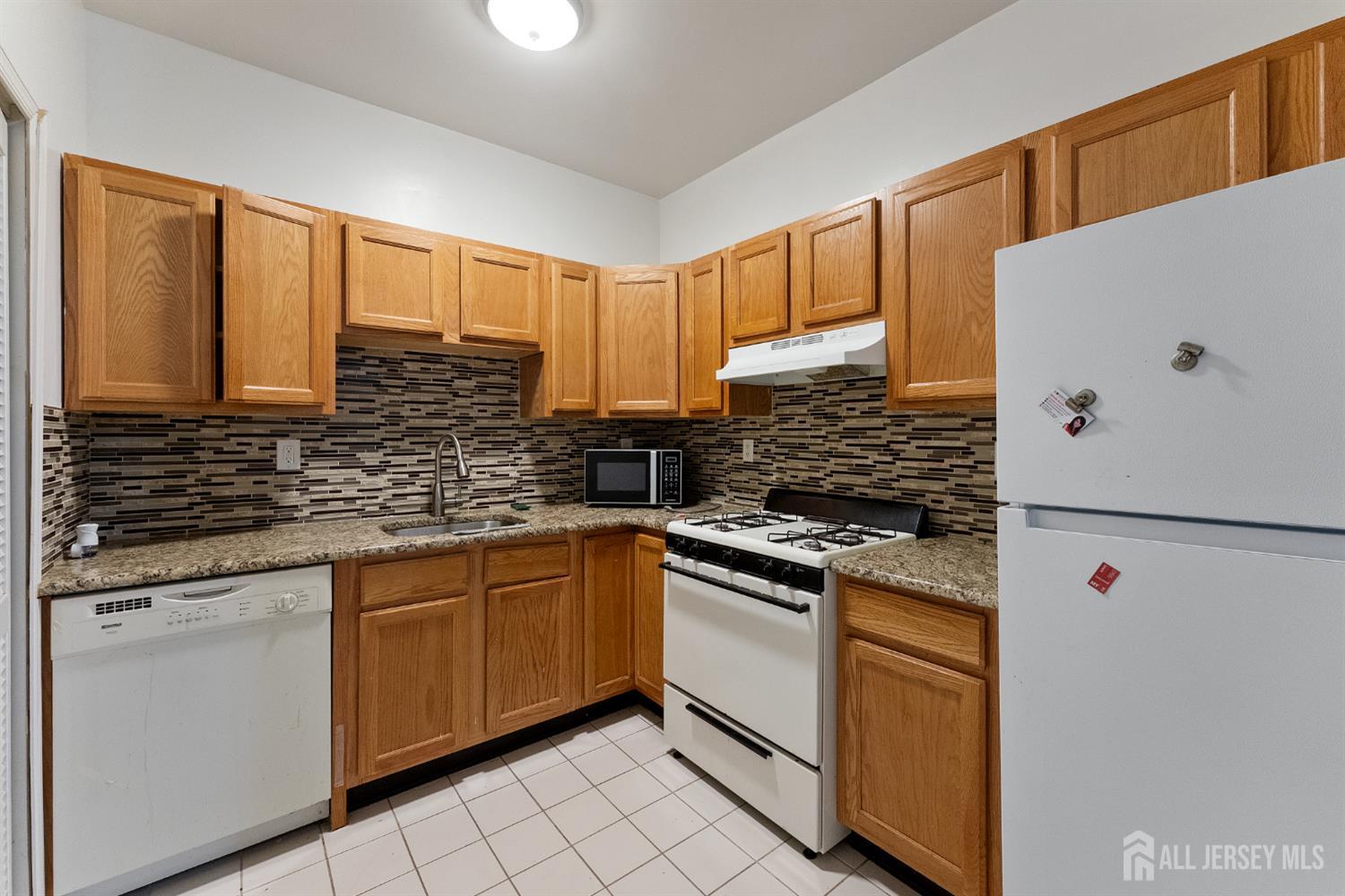 128 Remsen Avenue, Unit A New Brunswick, NJ 08901 - Photo 8 of 18 a kitchen with stainless steel appliances granite countertop a refrigerator sink and white cabinets