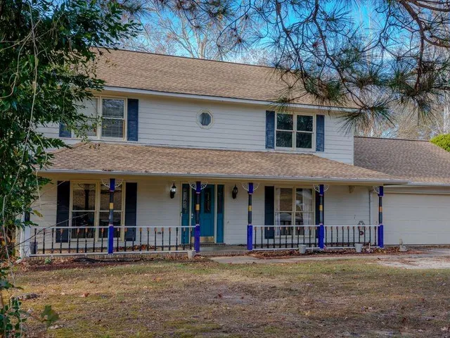 a front view of a house with a yard and large tree