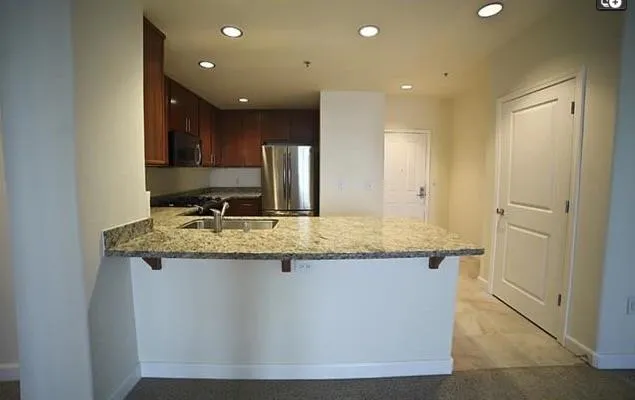 a kitchen with kitchen island granite countertop wooden cabinets and refrigerator