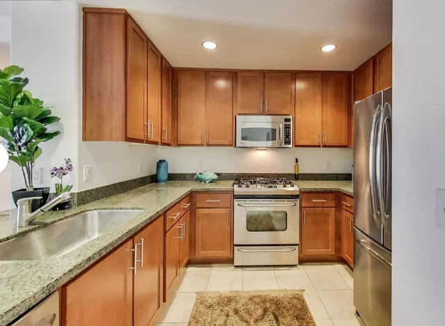 a kitchen with stainless steel appliances granite countertop a sink a stove and a refrigerator
