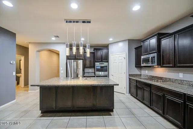 a kitchen with stainless steel appliances granite countertop a stove a sink and a refrigerator