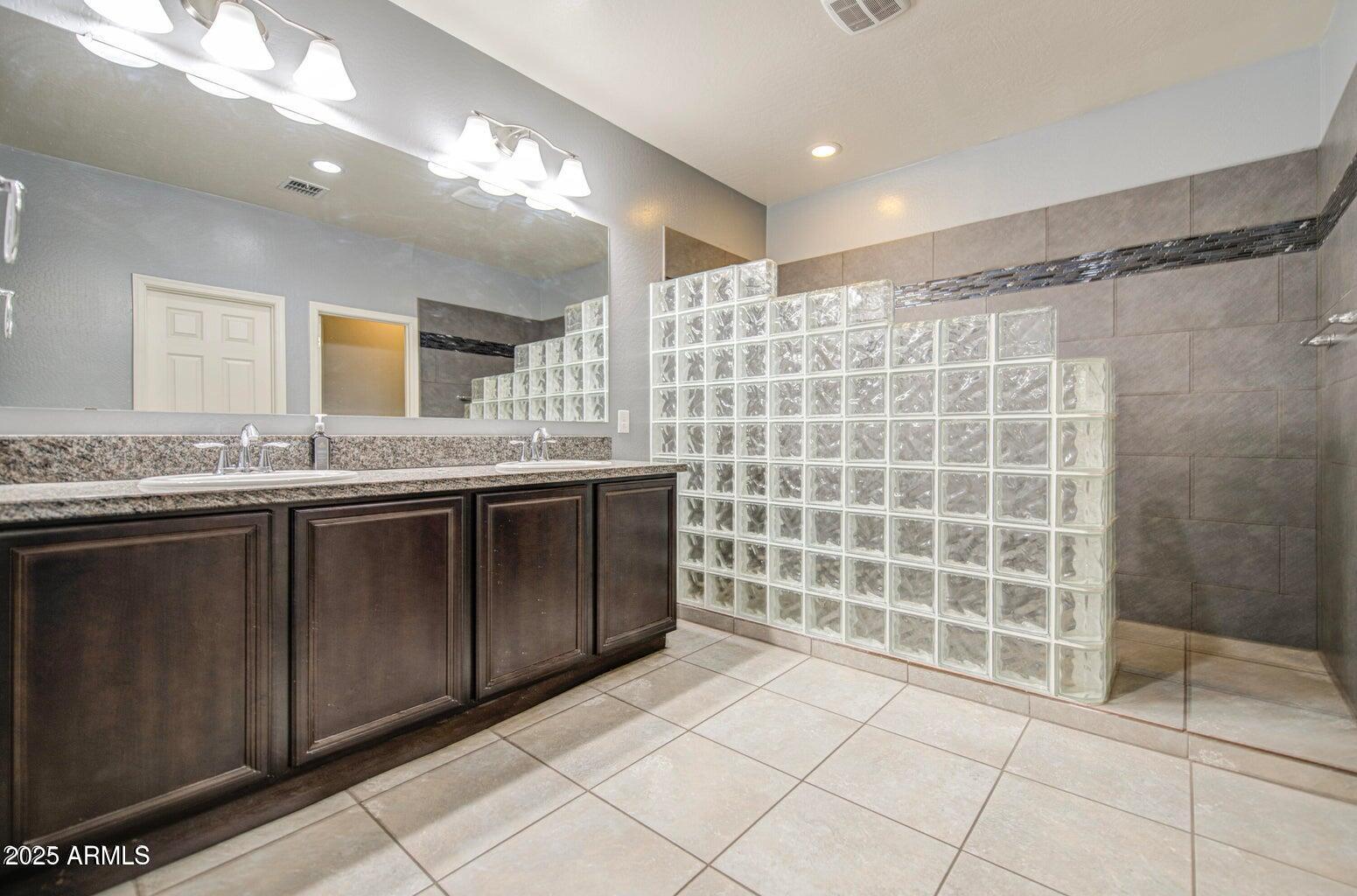 6815 South 19th Lane Phoenix, AZ 85041 - Photo 21 of 40 a bathroom with a granite countertop sink a mirror and a shower