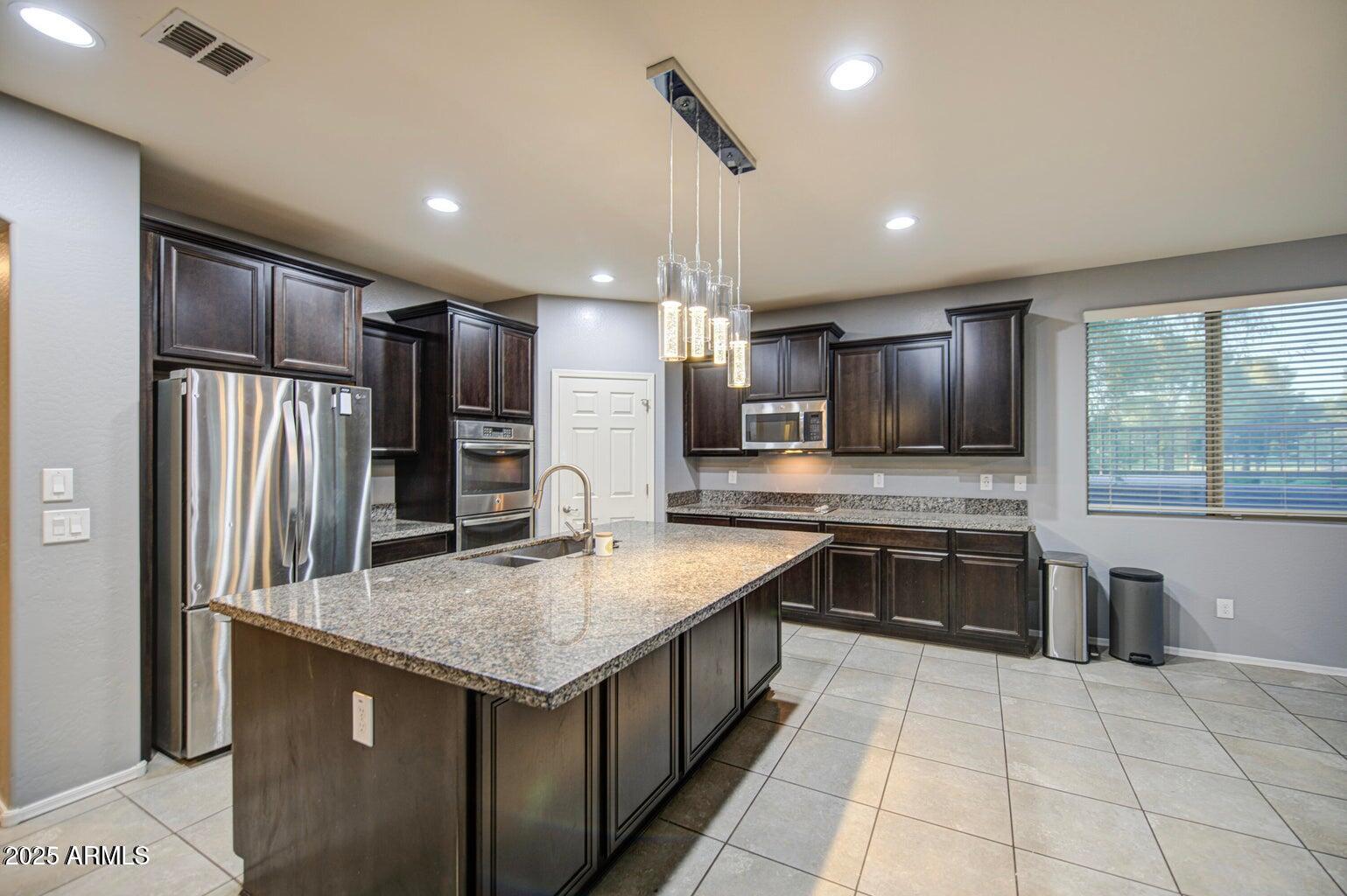 6815 South 19th Lane Phoenix, AZ 85041 - Photo 3 of 40 a kitchen with stainless steel appliances granite countertop a sink stove and refrigerator