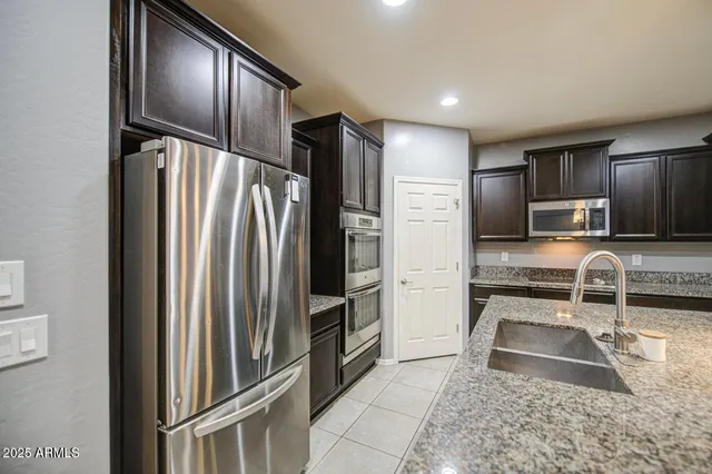 a kitchen with granite countertop a refrigerator and a sink