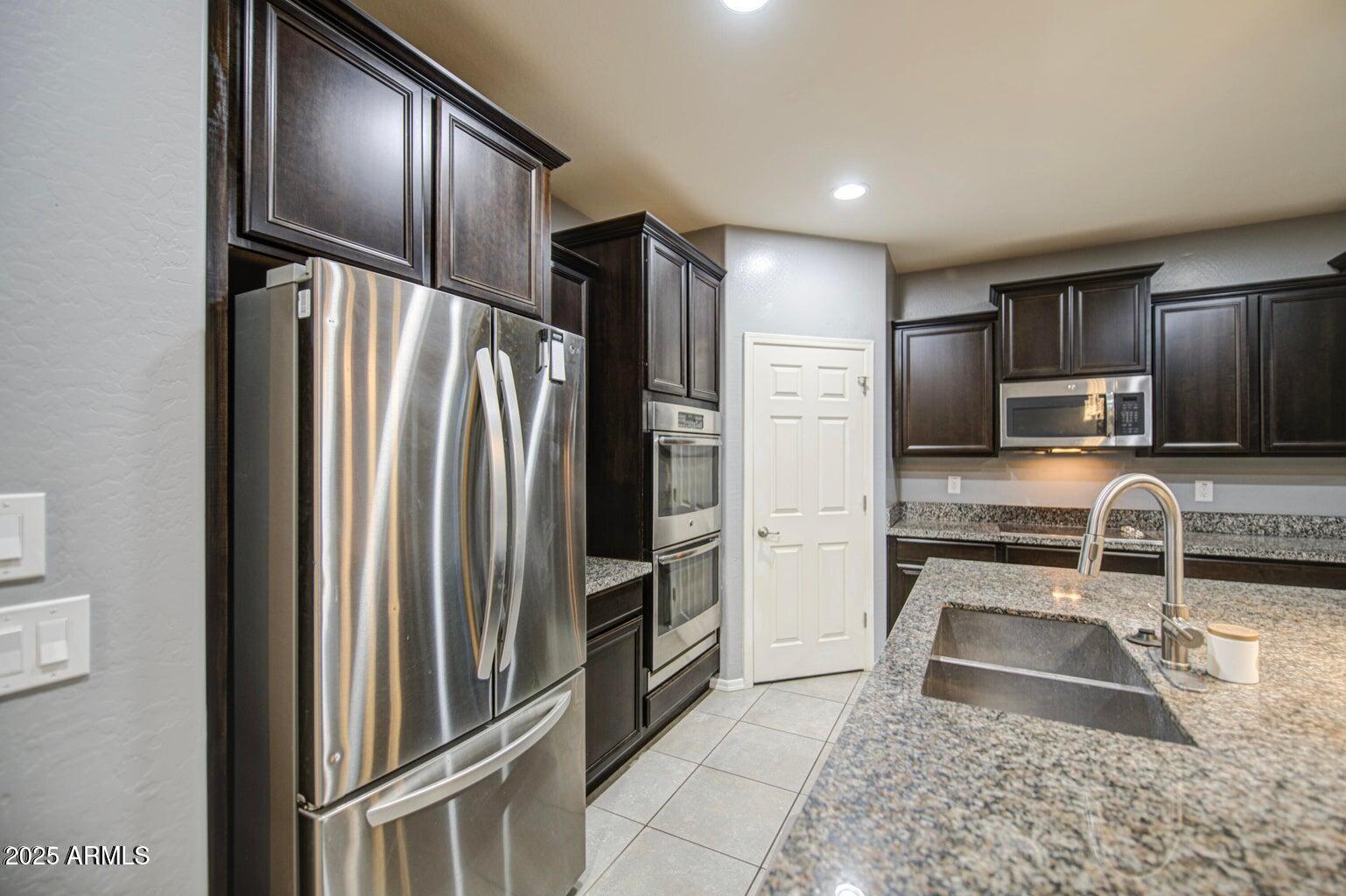 6815 South 19th Lane Phoenix, AZ 85041 - Photo 4 of 40 a kitchen with granite countertop a refrigerator and a sink