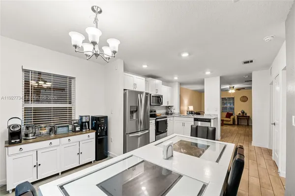 a kitchen with stainless steel appliances kitchen island granite countertop a refrigerator a sink a stove with island cabinets and wooden floor