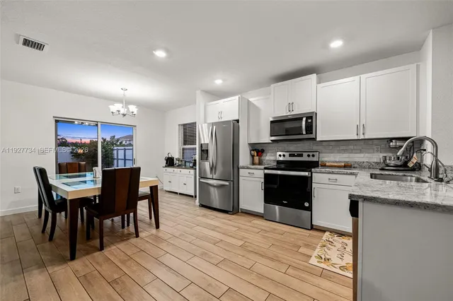 a kitchen with stainless steel appliances a kitchen island hardwood floor sink and stove