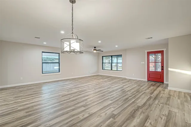 a view of an empty room with wooden floor and a ceiling fan