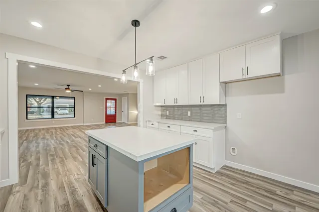 a view of an empty room with wooden floor and a ceiling fan