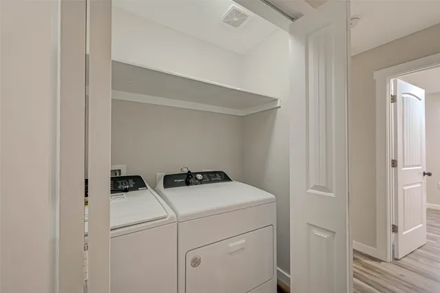 an empty room with wooden floor cabinet and windows