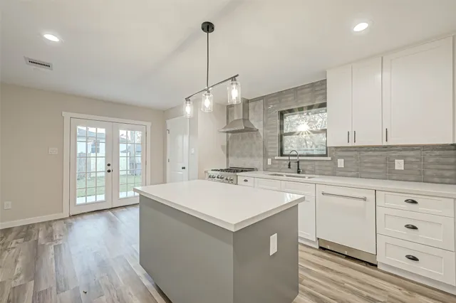 a kitchen with a sink a center island wooden floor and cabinets