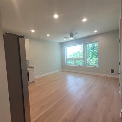 a open kitchen with stainless steel appliances granite countertop a refrigerator a sink dishwasher a stove and a dining table with wooden floor