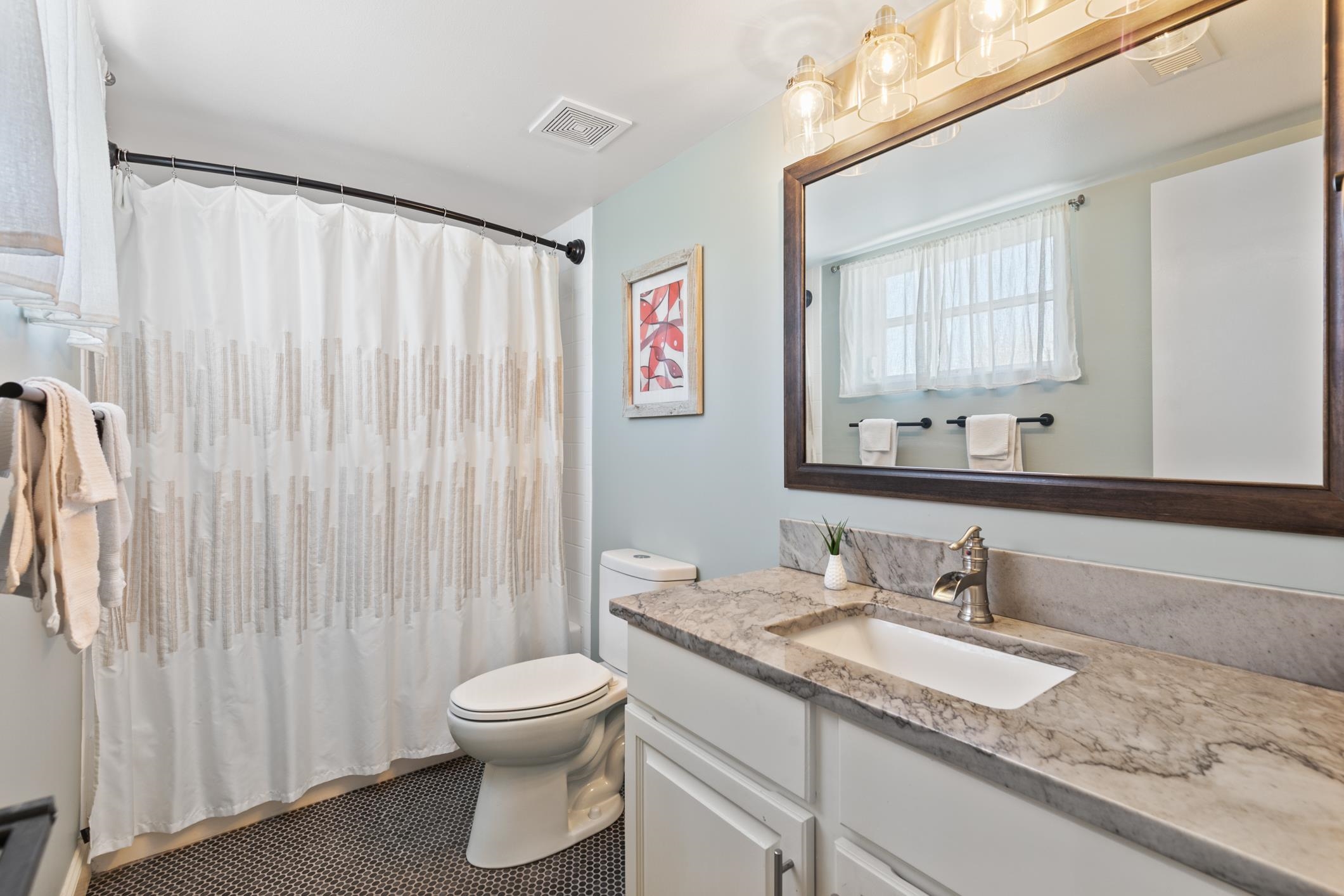 200 16th Street, Unit 202A St. Augustine, FL 32080 - Photo 24 of 39 a bathroom with a granite countertop sink a toilet and a mirror