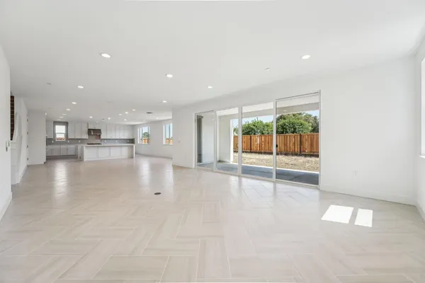 a view of an empty room with a kitchen view