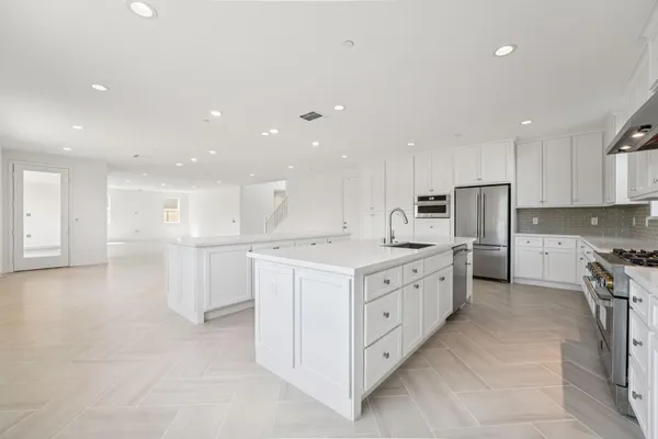a large kitchen with stainless steel appliances lots of white cabinets
