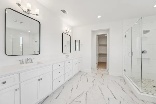 a spacious bathroom with double vanity sinks a mirror a vanity and a shower