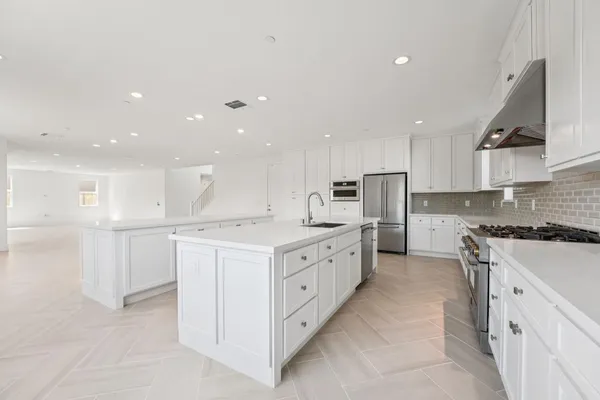 a large kitchen with stainless steel appliances and white cabinets