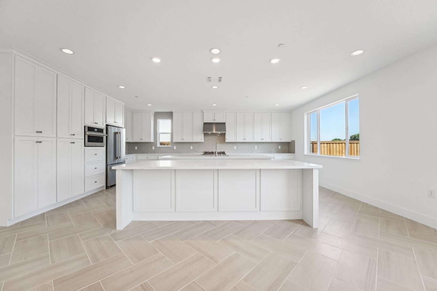 464 Trellis Way Brentwood, CA 94513 - Photo 9 of 22 a large white kitchen with kitchen island a sink a center island stainless steel appliances and a cabinets