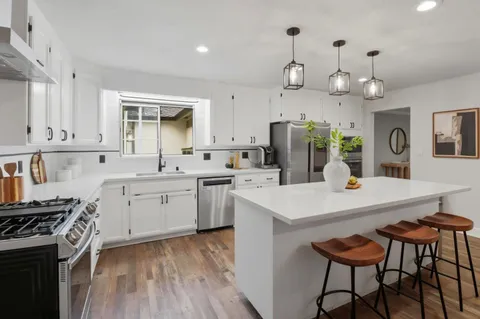 a kitchen with stainless steel appliances a stove a sink island and a refrigerator