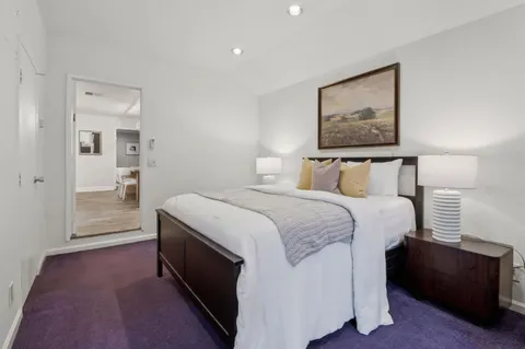 a spacious bedroom with a bed and painting on the wall