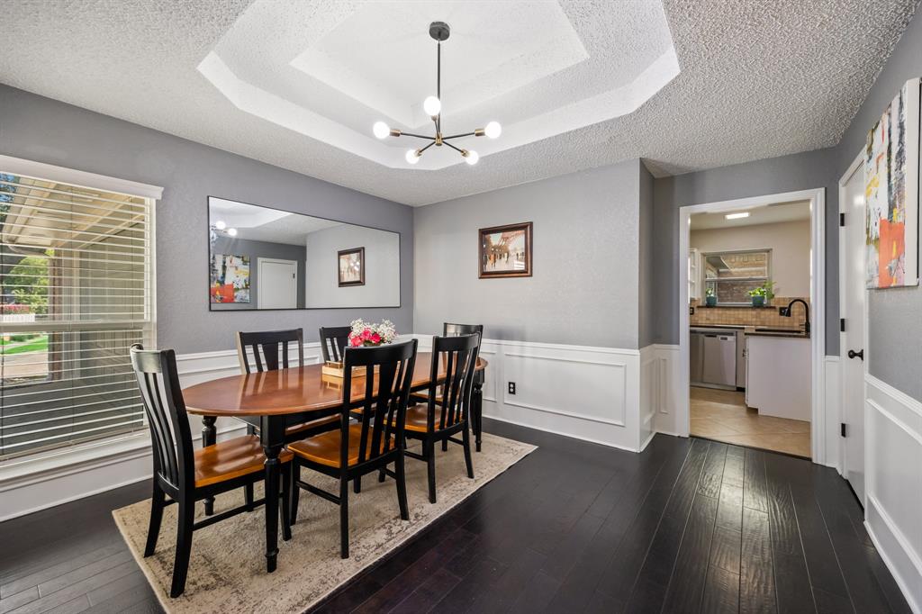 2807 Silverspring Road Carrollton, TX 75006 - Photo 12 of 37 Wainscoting, a stepped tray ceiling and large windows elevate the dining area.