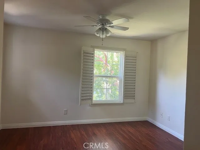 an empty room with wooden floor windows and fan
