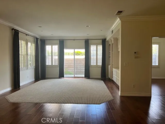 a large bedroom with wooden floor and windows