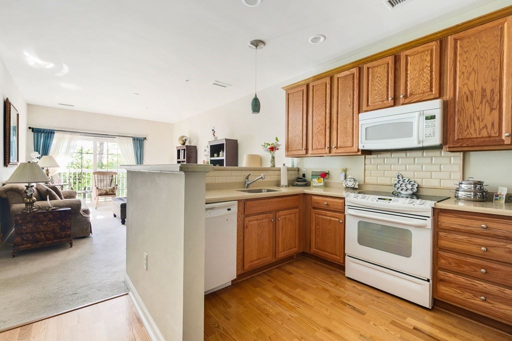 107 Clocktower Drive, Unit 107 Waltham, MA 02452 - Photo 3 of 13 a kitchen with stainless steel appliances granite countertop a stove a sink dishwasher and a refrigerator