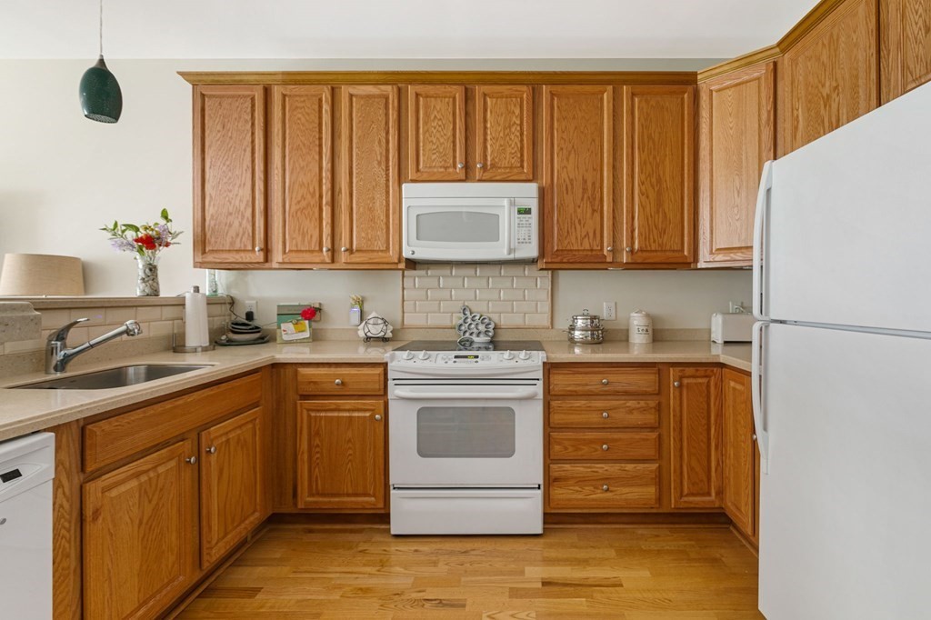 107 Clocktower Drive, Unit 107 Waltham, MA 02452 - Photo 4 of 13 a kitchen with stainless steel appliances granite countertop a stove a sink dishwasher and a refrigerator with wooden cabinets
