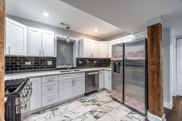 a kitchen with stainless steel appliances granite countertop a refrigerator a sink and white cabinets