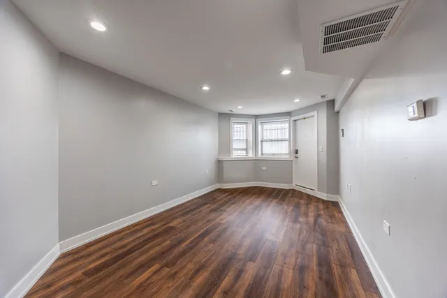 a view of an empty room with wooden floor and window