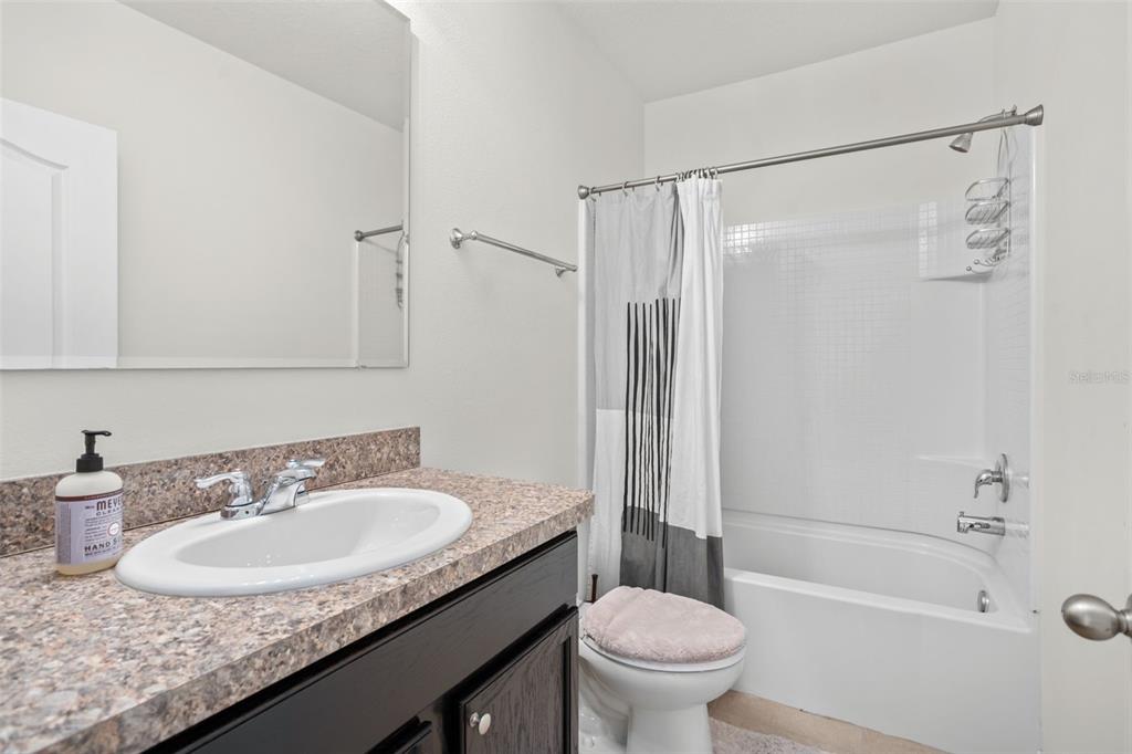 3449 Seneca Club Loop, Unit 24101 Orlando, FL 32808 - Photo 18 of 29 a bathroom with a granite countertop sink a toilet and shower