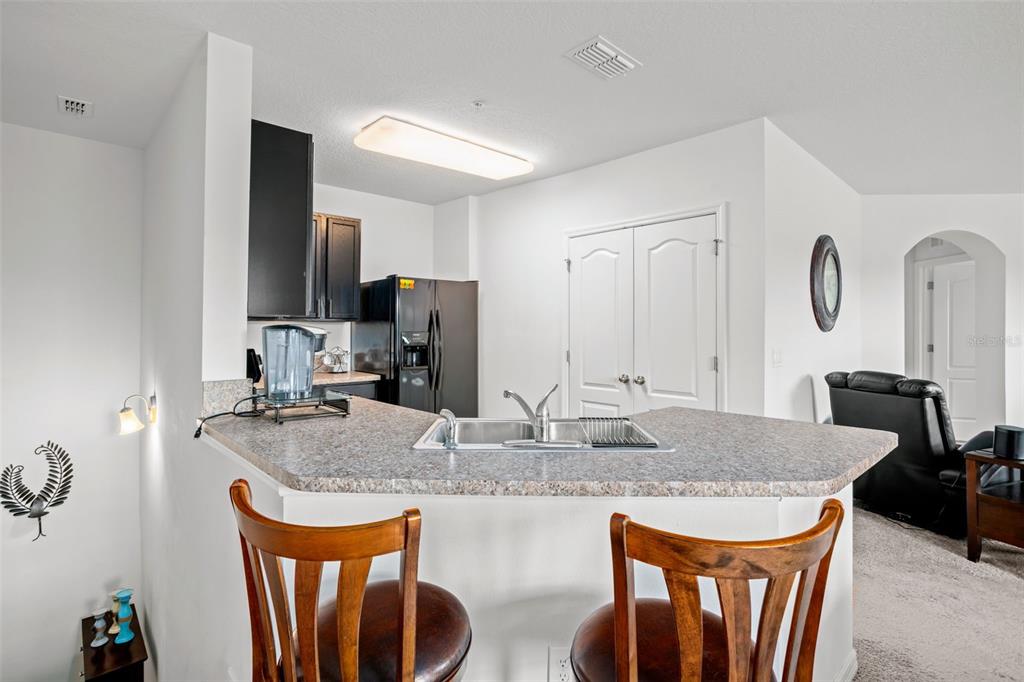 3449 Seneca Club Loop, Unit 24101 Orlando, FL 32808 - Photo 3 of 29 a kitchen with granite countertop kitchen island stainless steel appliances a sink refrigerator stove and microwave