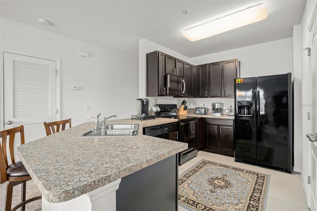 3449 Seneca Club Loop, Unit 24101 Orlando, FL 32808 - Photo 4 of 29 a kitchen with stainless steel appliances granite countertop a sink refrigerator and cabinets