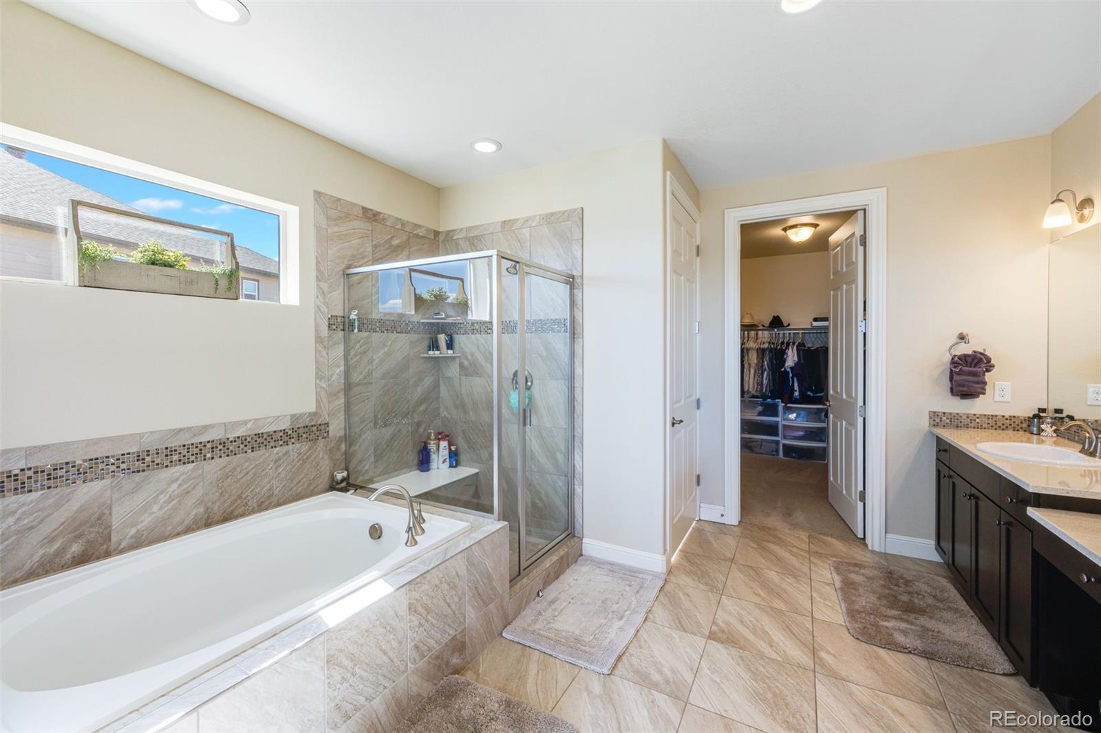 8474 Poppy Street Arvada, CO 80007 - Photo 14 of 40 a bathroom with a tub a sink and a large mirror
