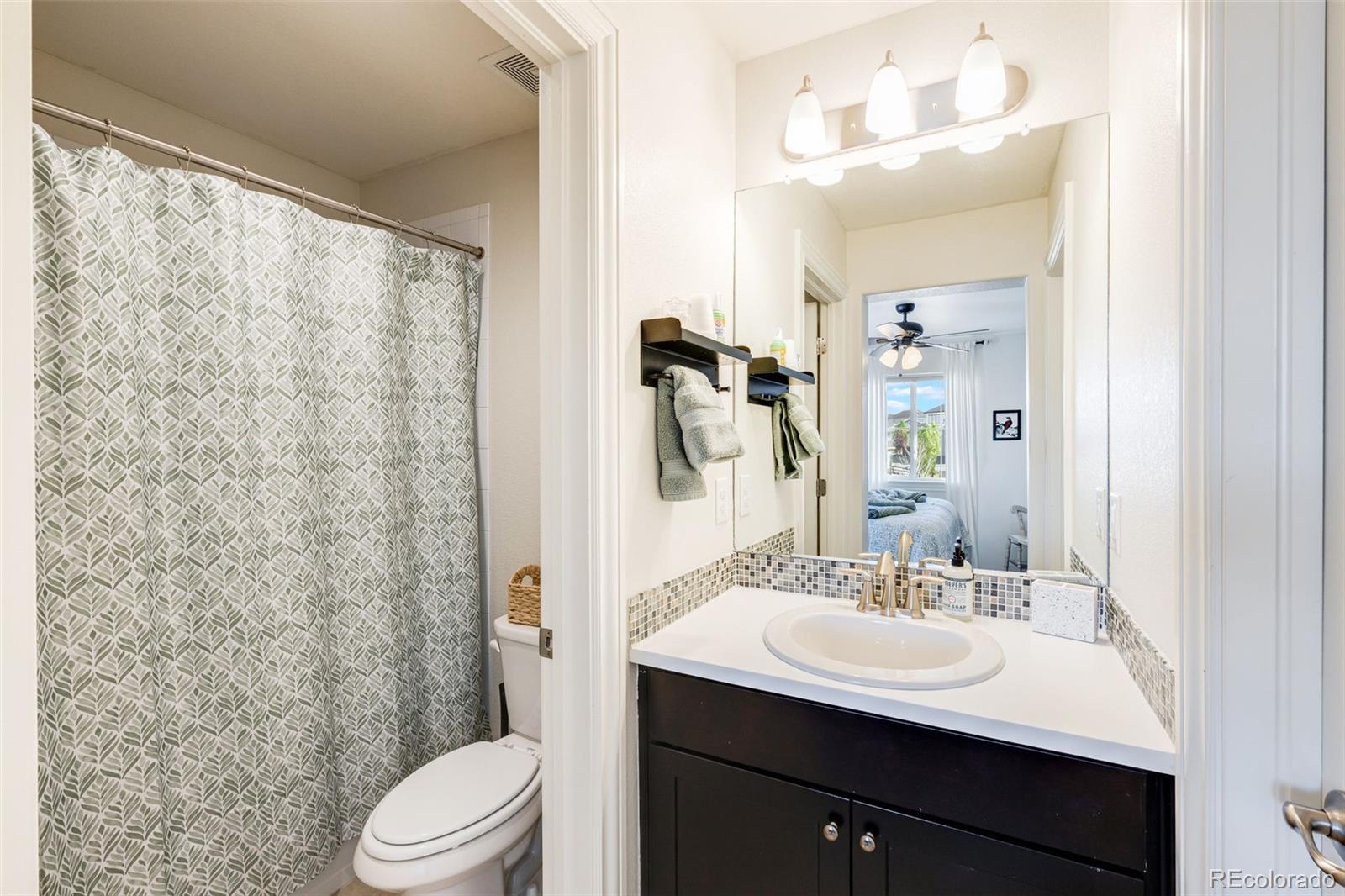 8474 Poppy Street Arvada, CO 80007 - Photo 24 of 40 a bathroom with a sink toilet a mirror and shower