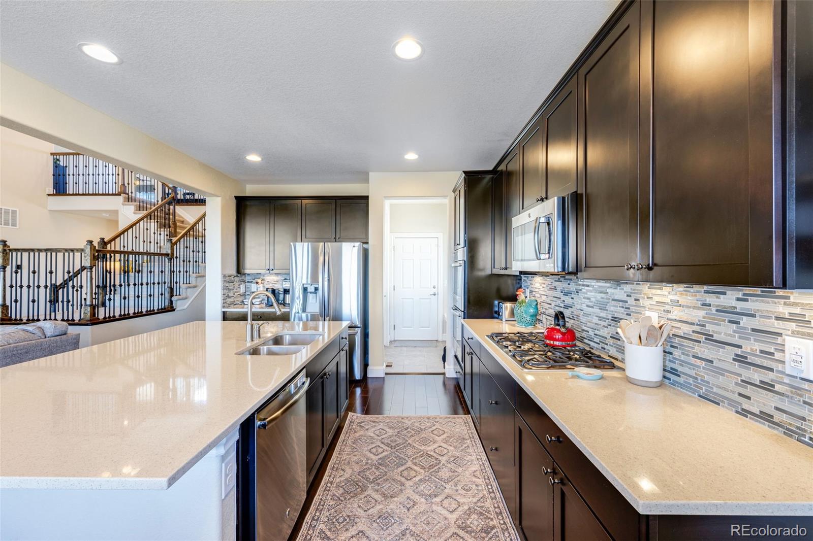 8474 Poppy Street Arvada, CO 80007 - Photo 4 of 40 a kitchen with stainless steel appliances granite countertop a sink stove and cabinets