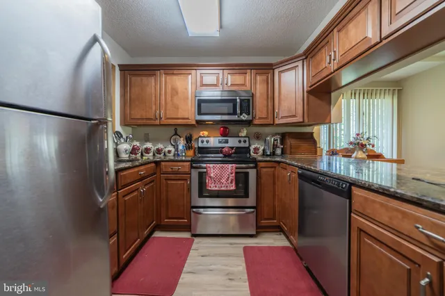 a kitchen with granite countertop a refrigerator and a stove top oven