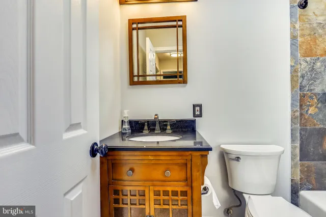 a bathroom with a granite countertop toilet sink and mirror